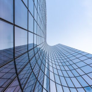 Blue curved glass skyscraper facade against sky
