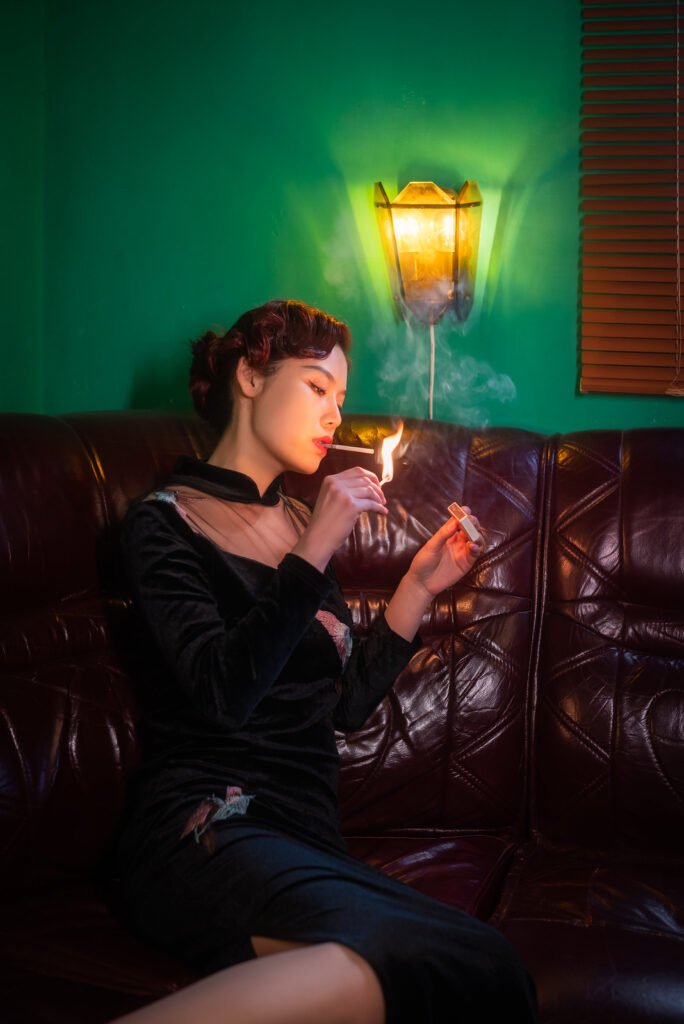 Young woman on a leather couch lighting a cigarette