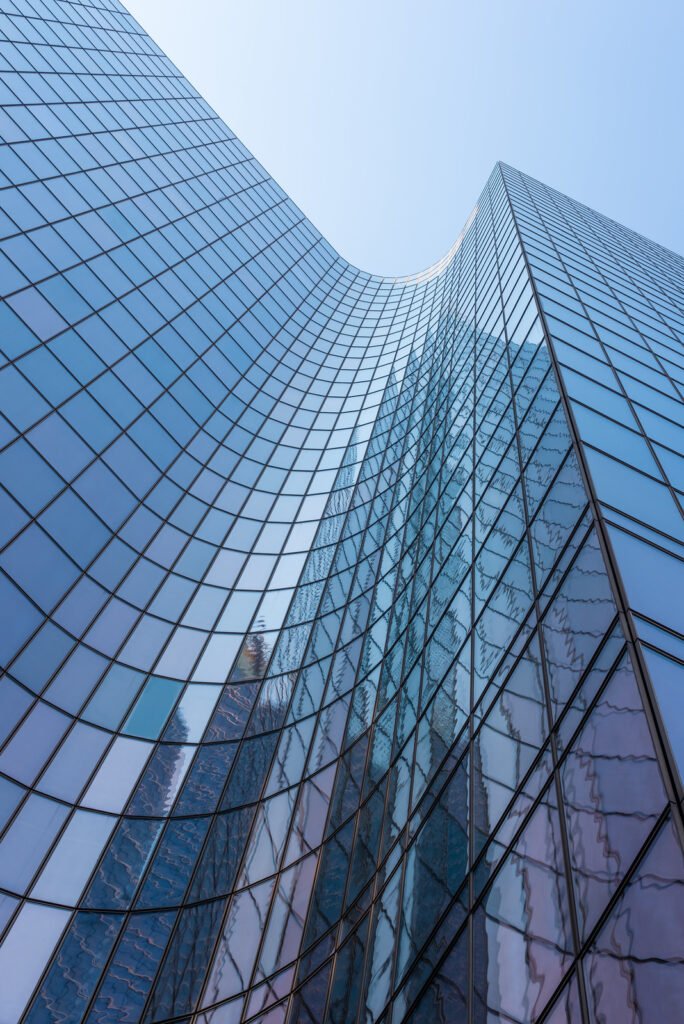 Blue curved glass skyscraper facade against sky