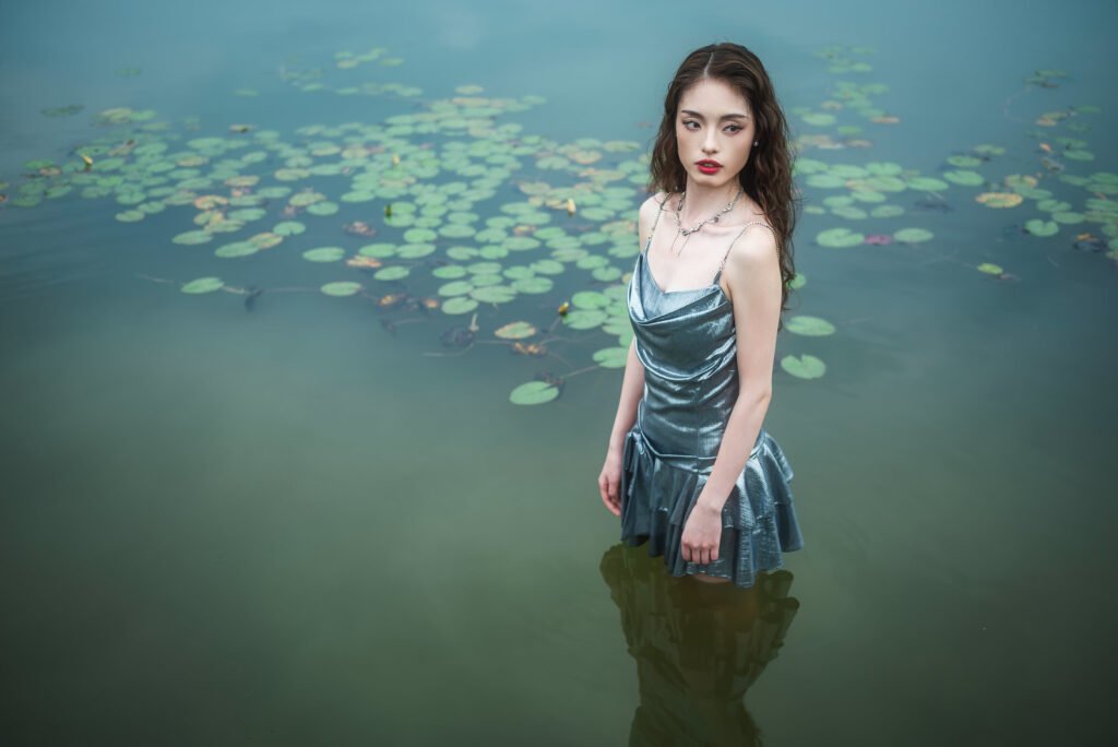 Young woman standing in a lake with lily pads.