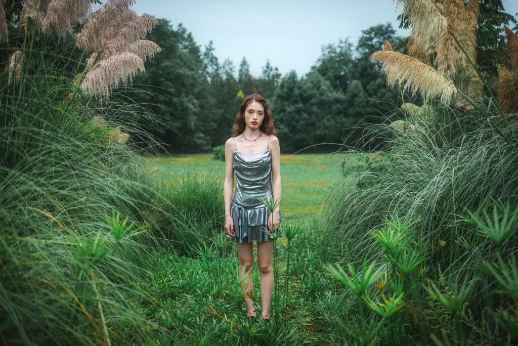 Portrait of a young woman standing in a field of tall grass