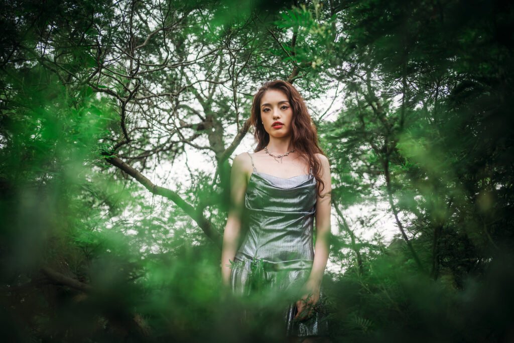 Portrait of a beautiful woman wearing a silver dress standing in a forest