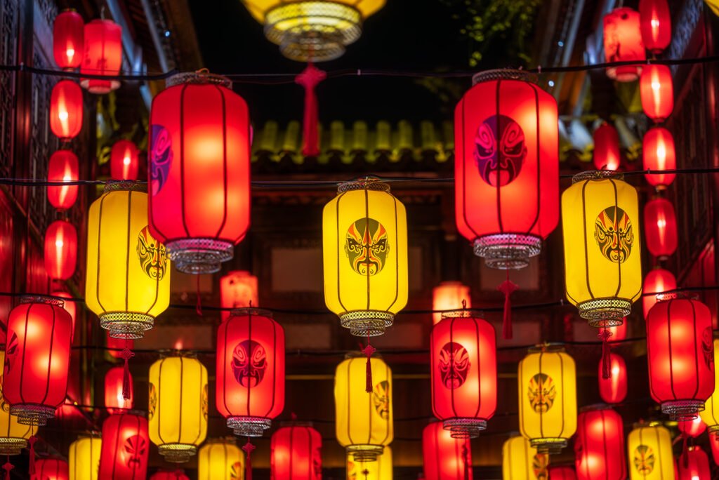 Red and yellow Chinese lanterns with Sichuan opera faces illuminated at night