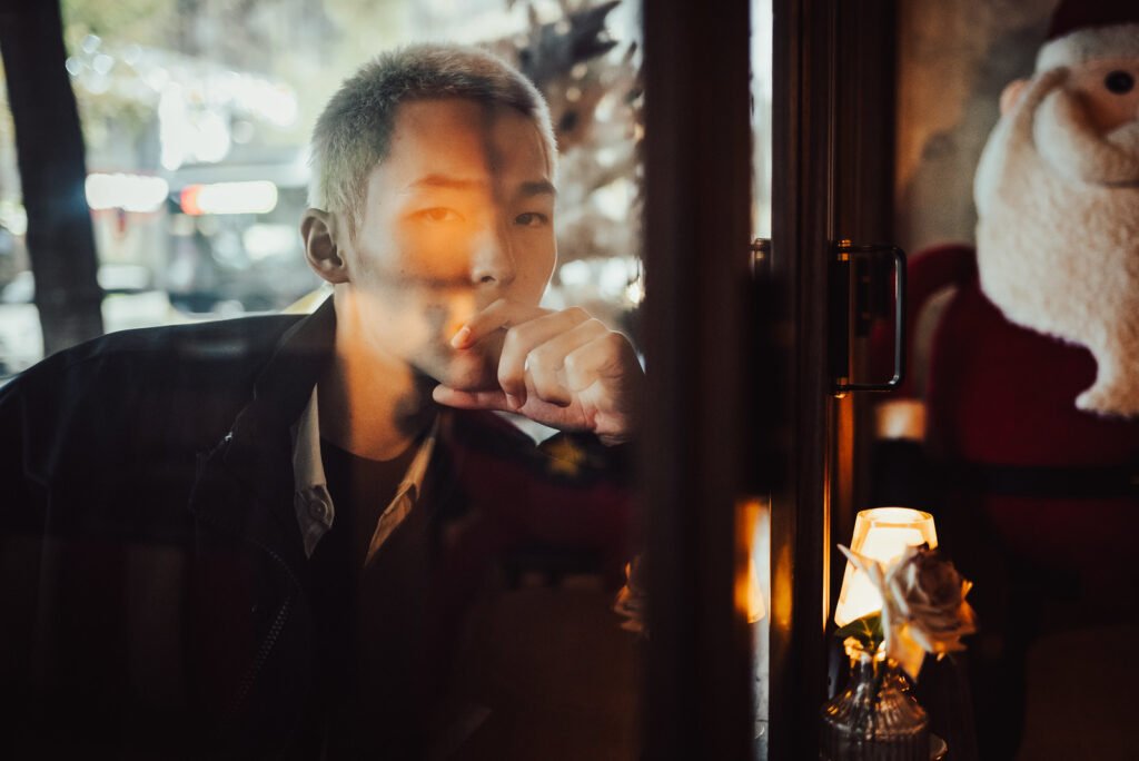 Young man looking through window in contemplation