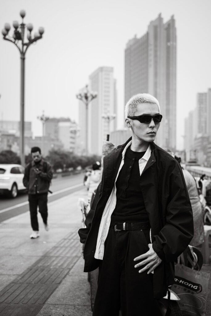 Young Asian man wearing sunglasses and a stylish outfit in the city.