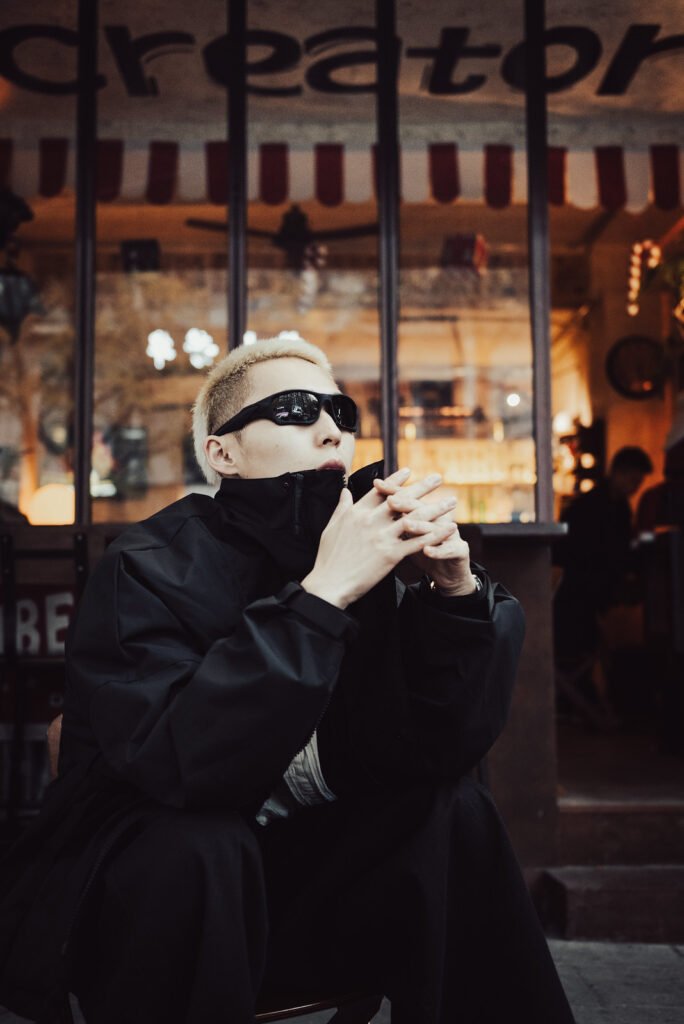 Young man with sunglasses sitting outside a cafe.