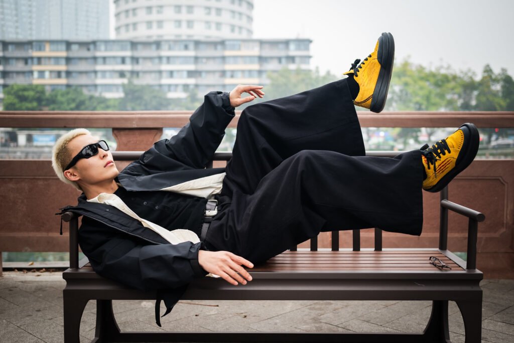 Young man in black outfit relaxing on a bench.