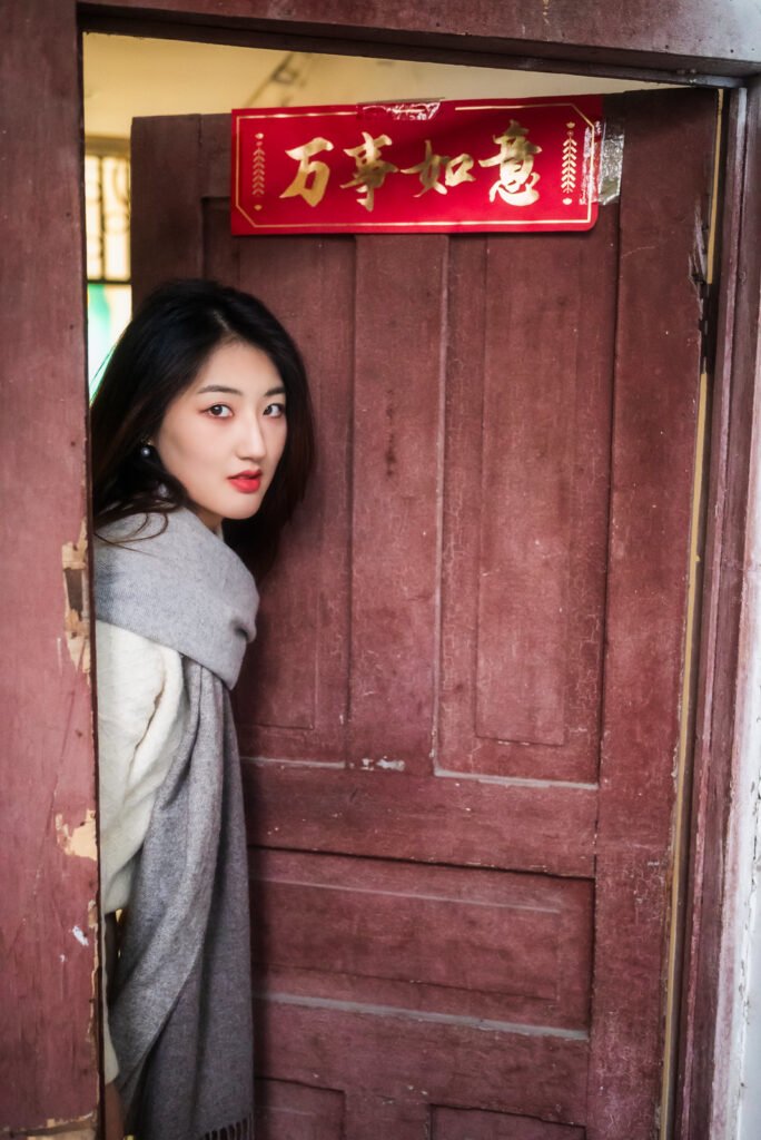 Young woman standing in front of a red door.