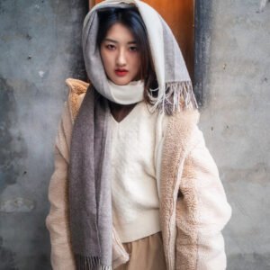 Young woman in a stylish winter outfit with a scarf wrapped around her head and neck.