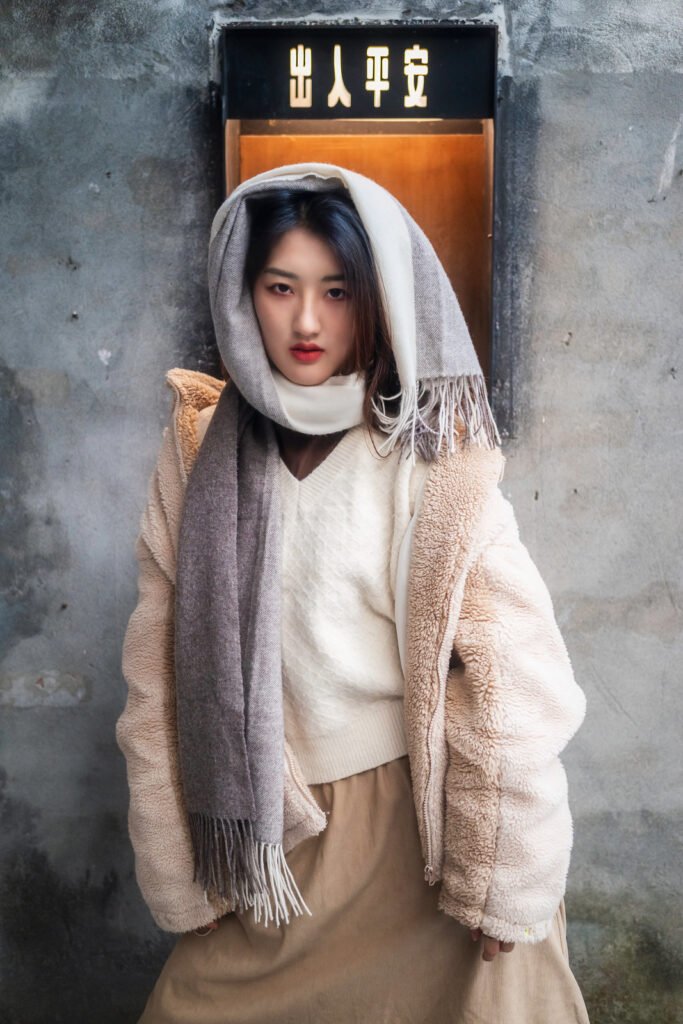 Young woman in a stylish winter outfit with a scarf wrapped around her head and neck.