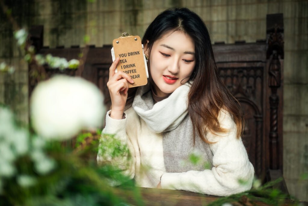 Young woman holding a sign that says You Drink Tea I Drink Coffee Dear