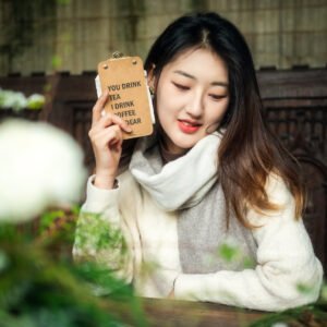 Young woman holding a sign that says You Drink Tea I Drink Coffee Dear