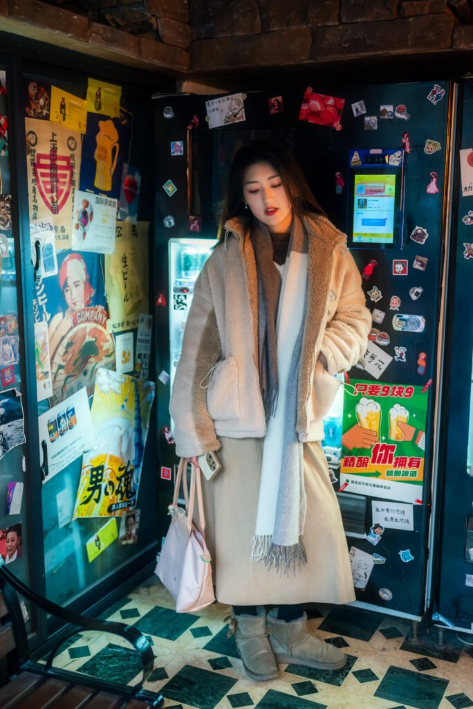 Young woman standing in front of a wall full of posters and advertisements.