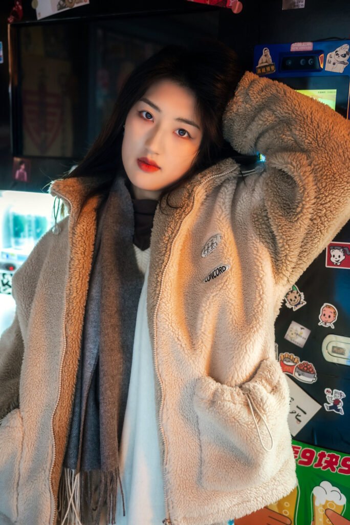 Young woman in a fuzzy coat standing in front of a vending machine.