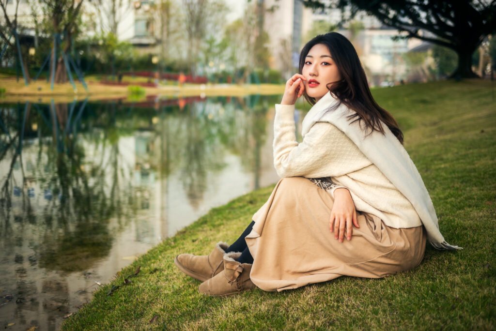 Young woman sitting on the grass by the lake.