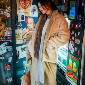Young woman standing in front of a wall full of posters and advertisements.