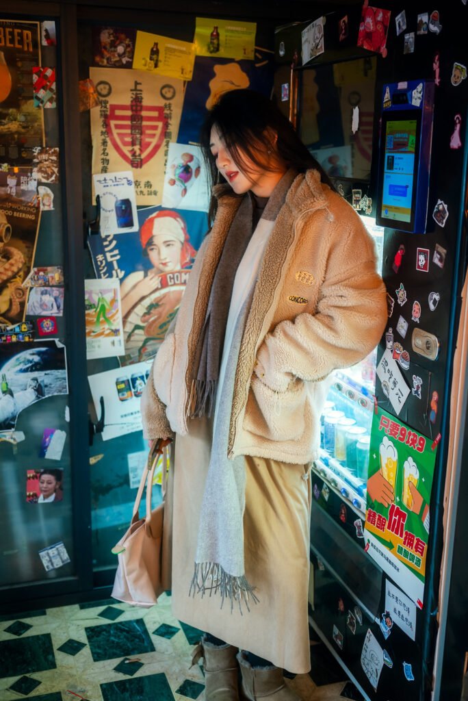 Young woman standing in front of a wall full of posters and advertisements.