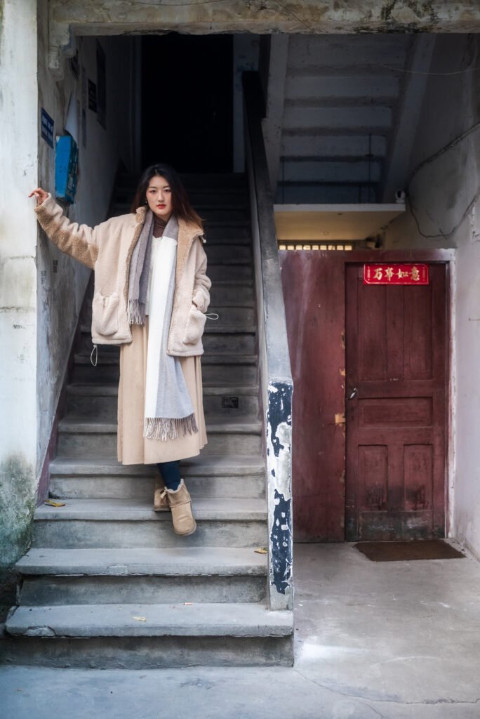 Young woman in a stylish winter outfit standing on the stairs.