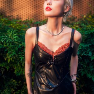 Portrait of a young woman with short blonde hair wearing a black leather dress.