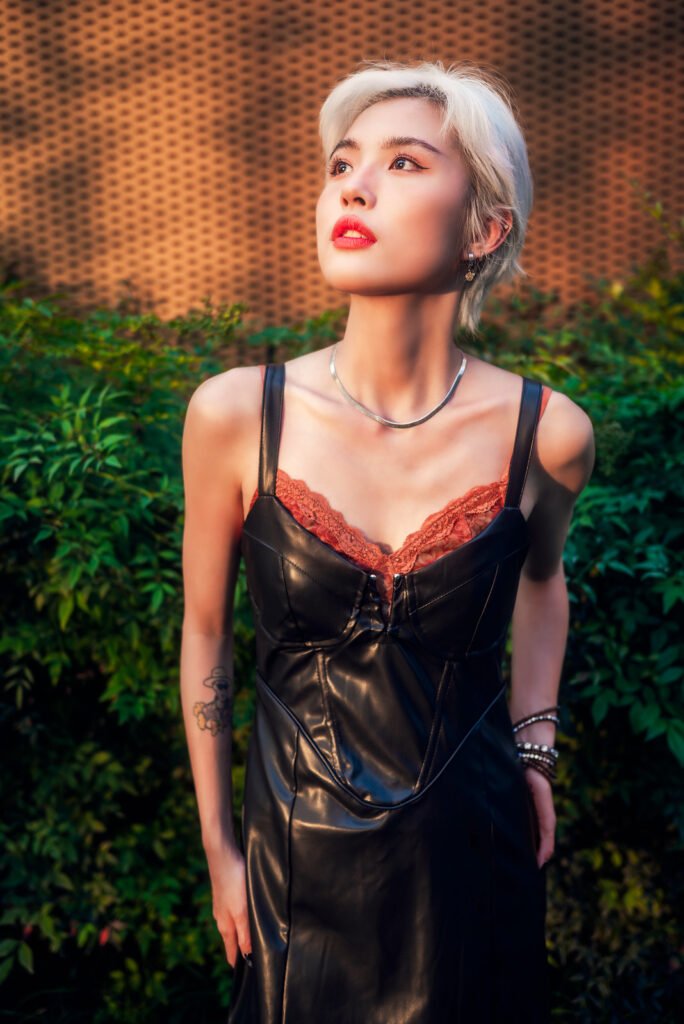 Portrait of a young woman with short blonde hair wearing a black leather dress.