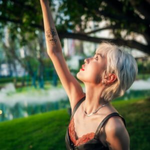 Blonde girl reaching for the sun in a park