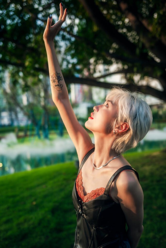 Blonde girl reaching for the sun in a park