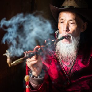 Portrait of a wise Chinese old man smoking a pipe.