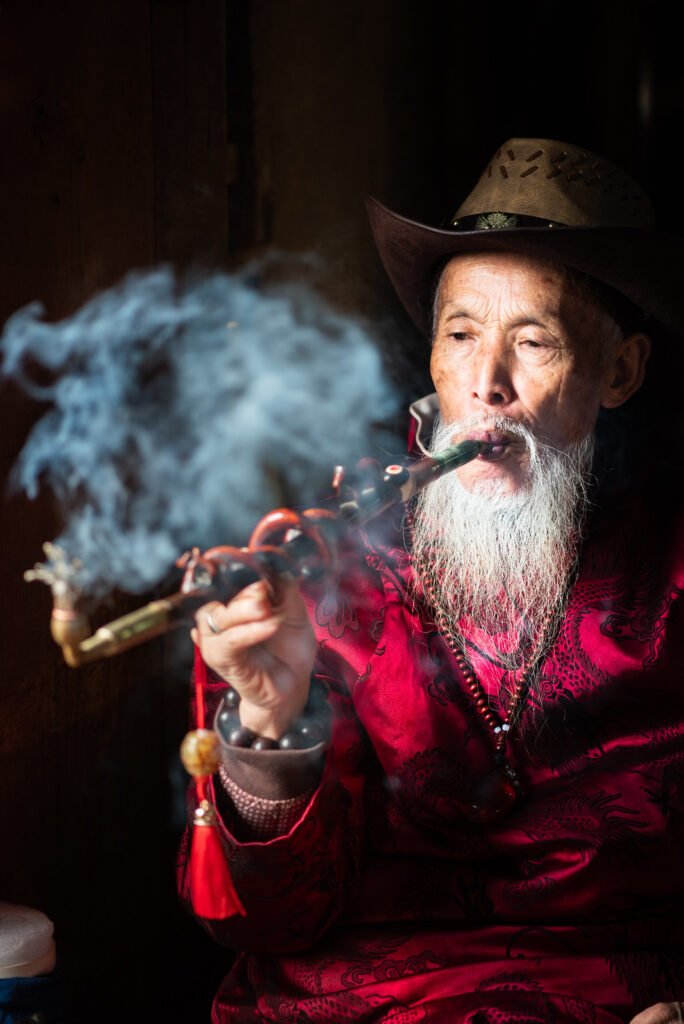 Portrait of a wise Chinese old man smoking a pipe.