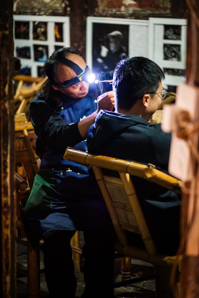Man getting his ear cleaned with traditional Chinese tools in a tea house