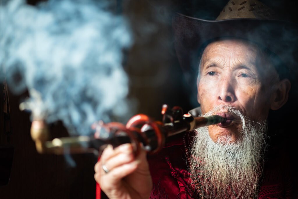 Portrait of an old chinese man smoking a traditional pipe in an ancient teahouse