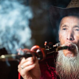 Portrait of an old chinese man smoking a traditional pipe in an ancient teahouse