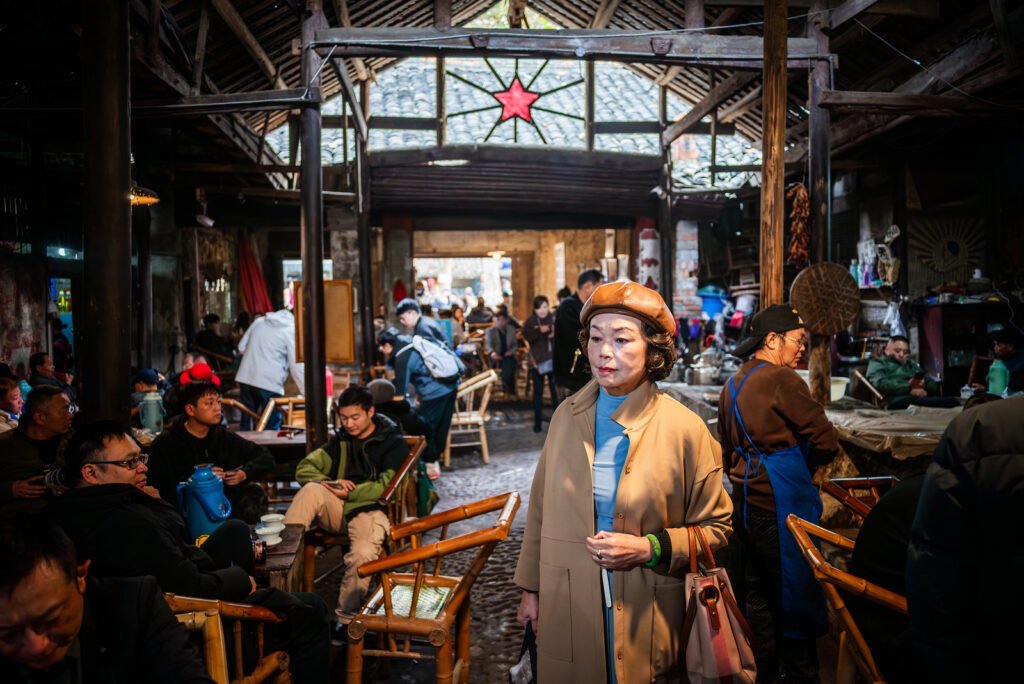 Elderly woman walking through a busy Chinese ancient tea house