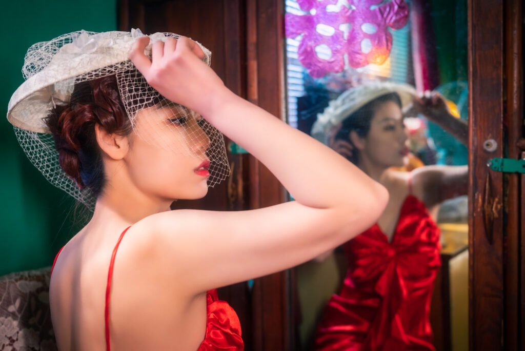 Young woman with a red and a white hat reflecting in a mirror