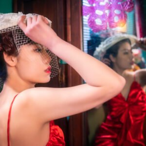 Young woman with a red and a white hat reflecting in a mirror