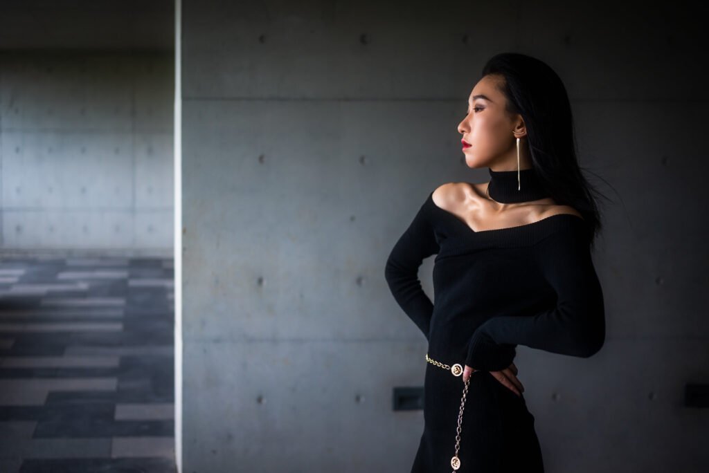 Elegant woman in black dress posing in a modern building.