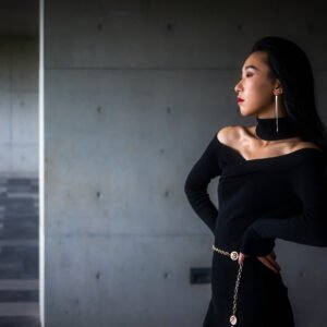 Elegant woman in black dress posing in a modern building.