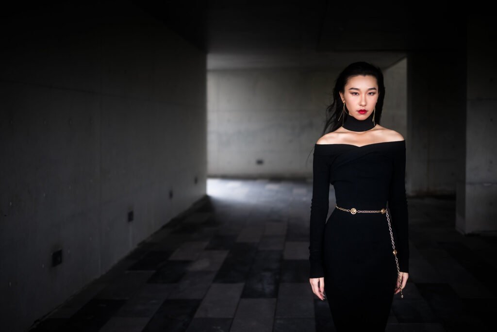 Elegant woman in black dress posing in dark room