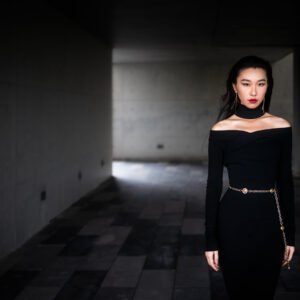Elegant woman in black dress posing in dark room