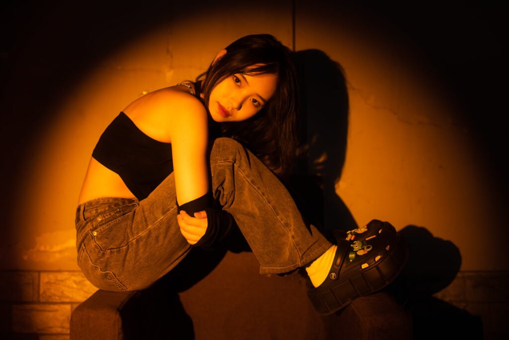 Young woman sitting on a couch in a dark street with orange lighting
