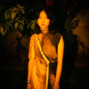 Portrait of a young woman standing in front of a dark background.