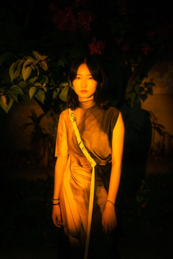 Portrait of a young woman standing in front of a dark background.