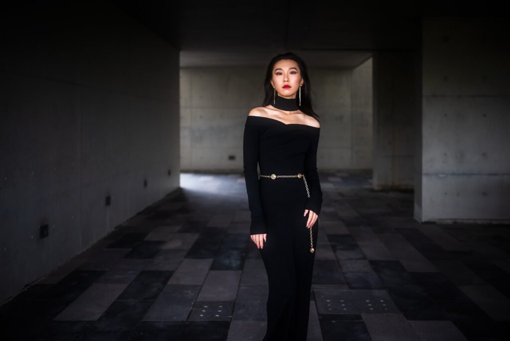 Elegant woman in black dress posing in dark corridor