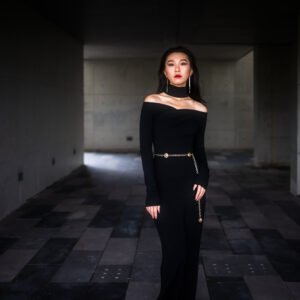 Elegant woman in black dress posing in dark corridor