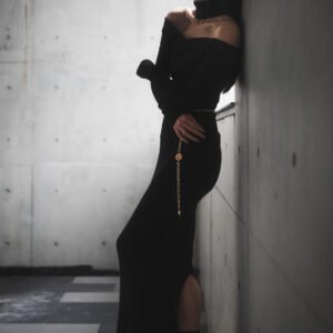 Young woman in black dress standing by the wall