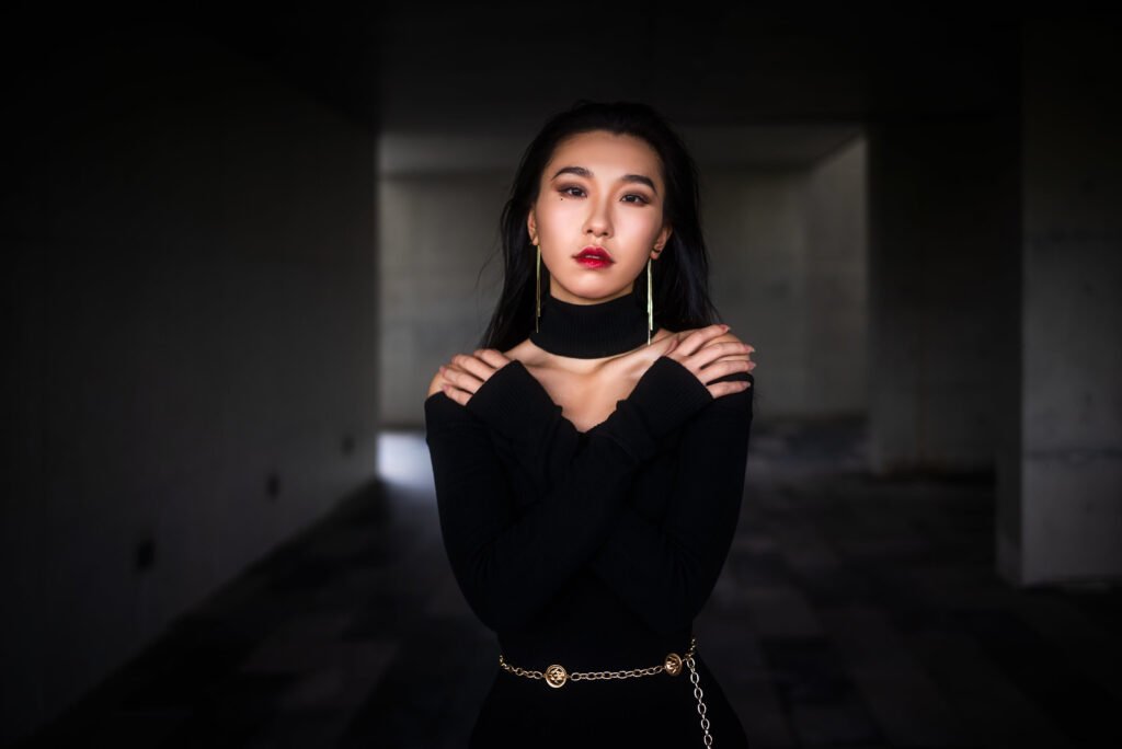 Elegant woman in black dress posing in dark room
