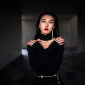 Elegant woman in black dress posing in dark room