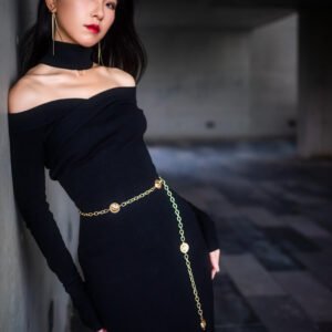 Elegant woman in black dress posing against a wall