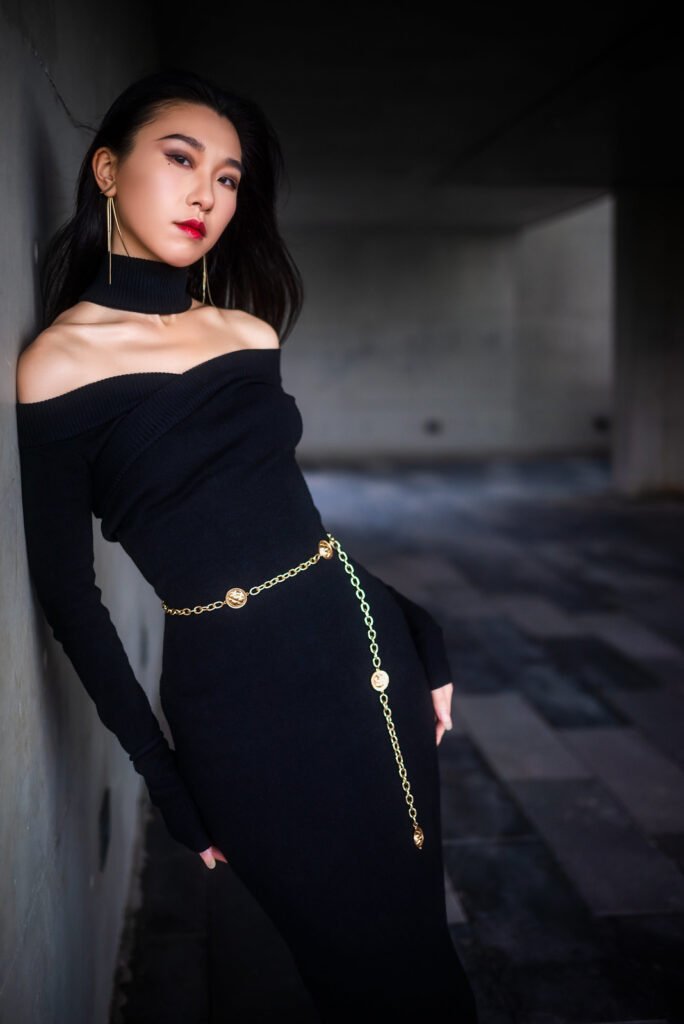 Elegant woman in black dress posing against a wall