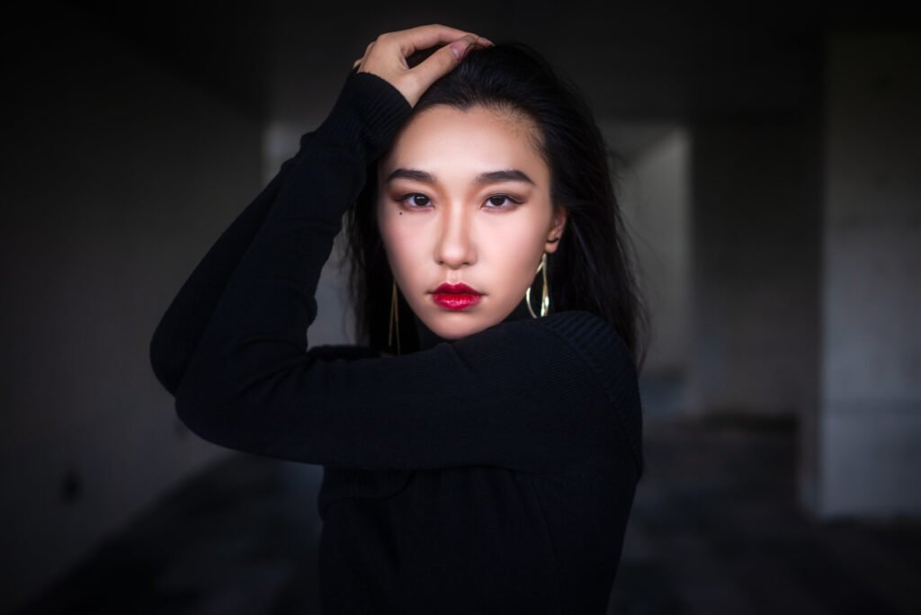 Elegant woman in black dress posing in dark room