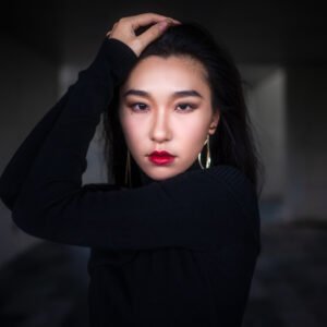 Elegant woman in black dress posing in dark room